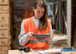 opearia de almacén con tablet y peto naranja